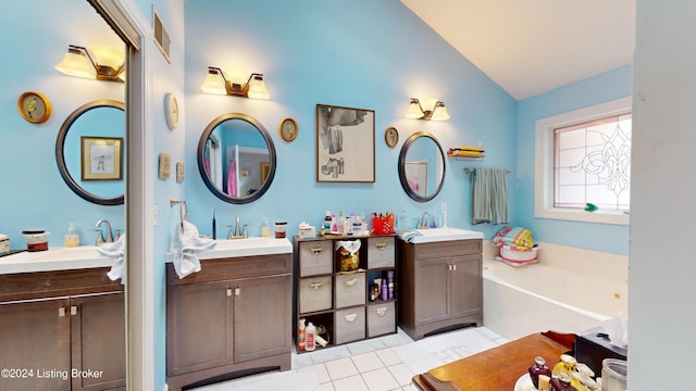 bathroom featuring tile patterned floors, vanity, lofted ceiling, and a tub to relax in