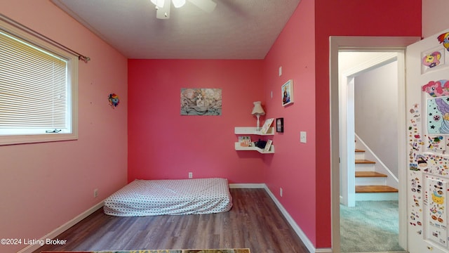 bedroom with hardwood / wood-style floors, ceiling fan, and a textured ceiling