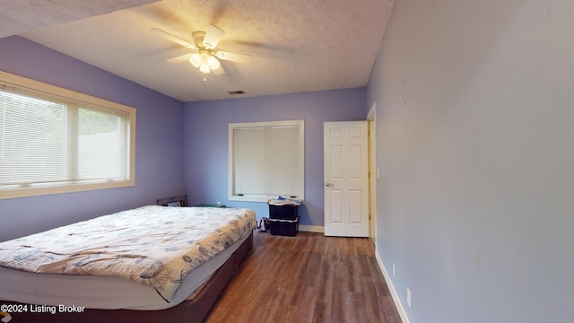 bedroom featuring ceiling fan, dark wood-type flooring, and a textured ceiling