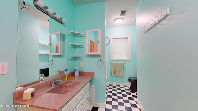 bathroom with a textured ceiling, vanity, and toilet