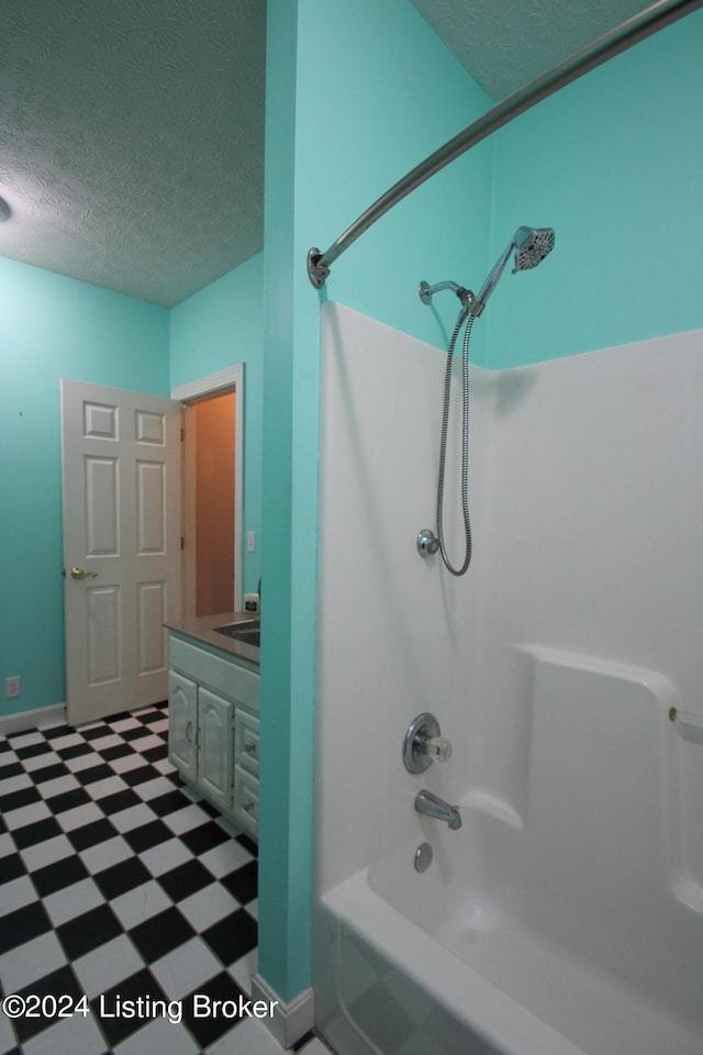 bathroom with vanity, a textured ceiling, and bathtub / shower combination