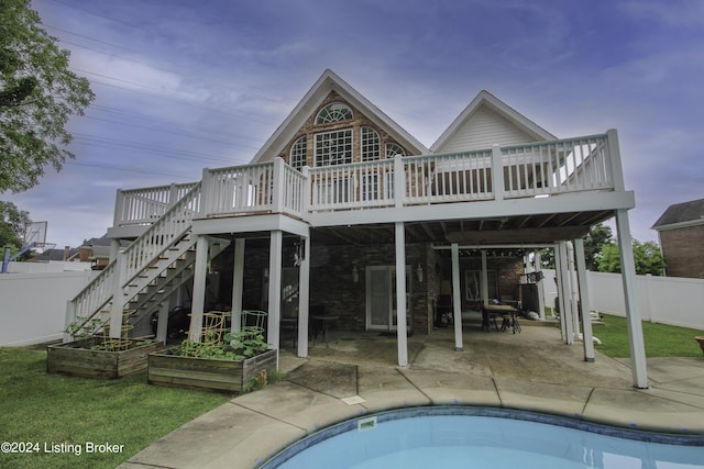 back of house featuring a patio, a pool side deck, and a lawn