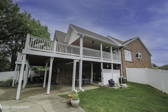 back house at dusk with a patio, a wooden deck, and a lawn