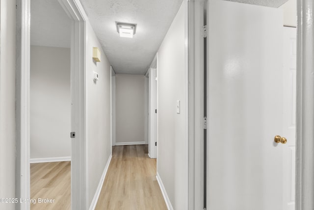 hallway featuring a textured ceiling and light hardwood / wood-style floors