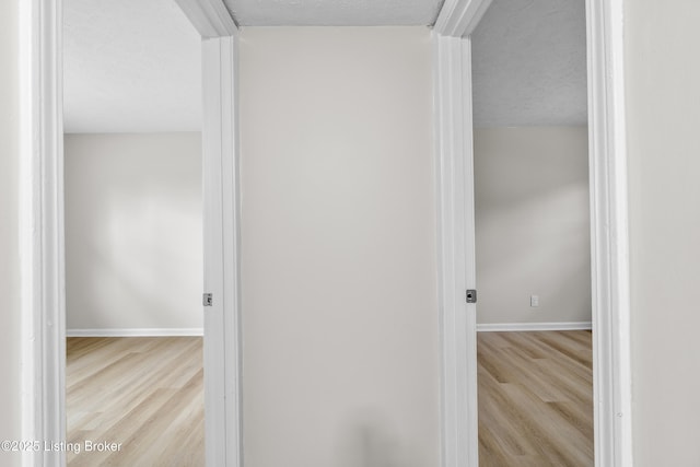 hall with a textured ceiling and light wood-type flooring