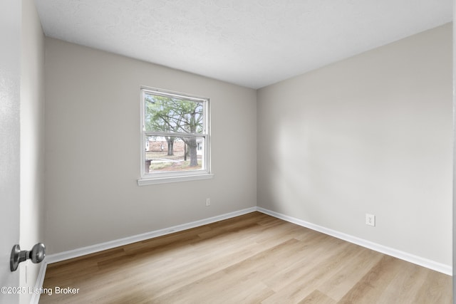 unfurnished room with a textured ceiling and light wood-type flooring