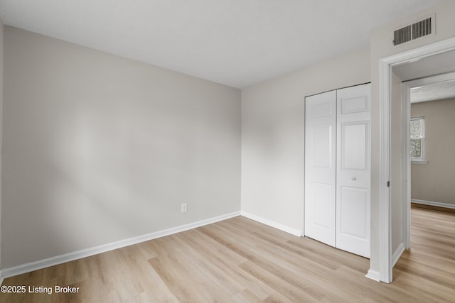 unfurnished bedroom featuring light hardwood / wood-style flooring and a closet