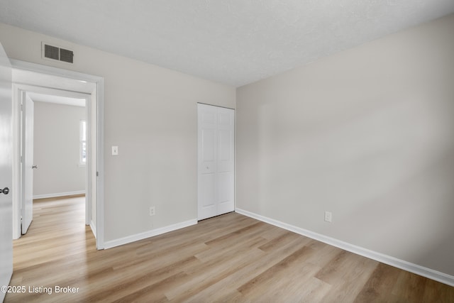 unfurnished bedroom with light hardwood / wood-style flooring and a closet