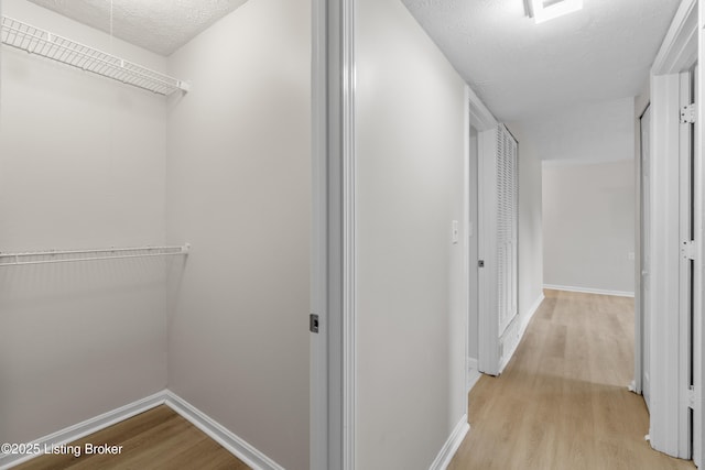 corridor featuring a textured ceiling and light hardwood / wood-style flooring