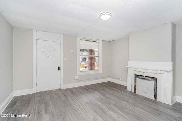 unfurnished living room with a fireplace, wood-type flooring, and a paneled ceiling