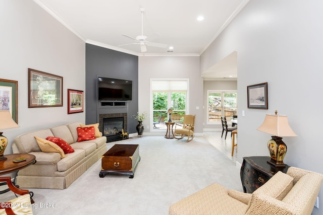 carpeted living room featuring ceiling fan, crown molding, and a fireplace