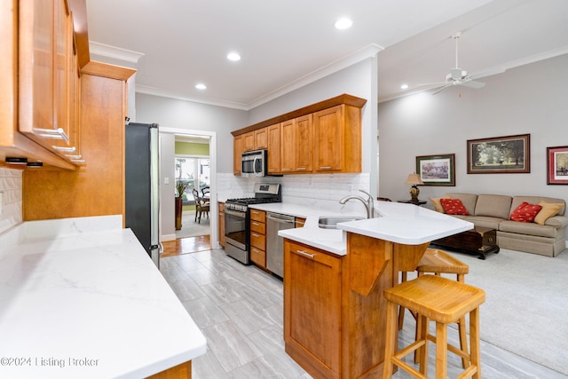 kitchen with sink, appliances with stainless steel finishes, tasteful backsplash, a kitchen bar, and kitchen peninsula