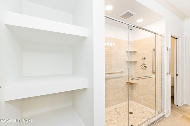 bathroom with a shower with door and tile patterned flooring