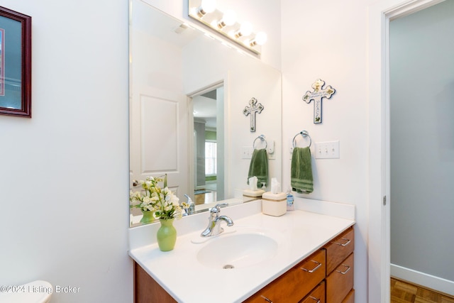 bathroom with parquet flooring, vanity, and toilet