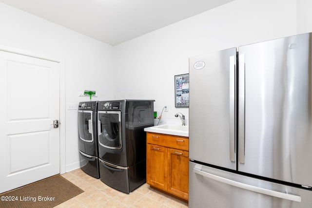 clothes washing area with independent washer and dryer, light tile patterned floors, and sink