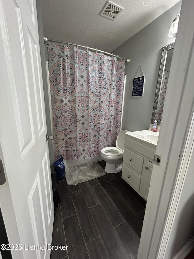 full bathroom featuring vanity, toilet, shower / bath combo, and a textured ceiling