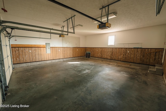 garage featuring electric panel, wood walls, and a garage door opener