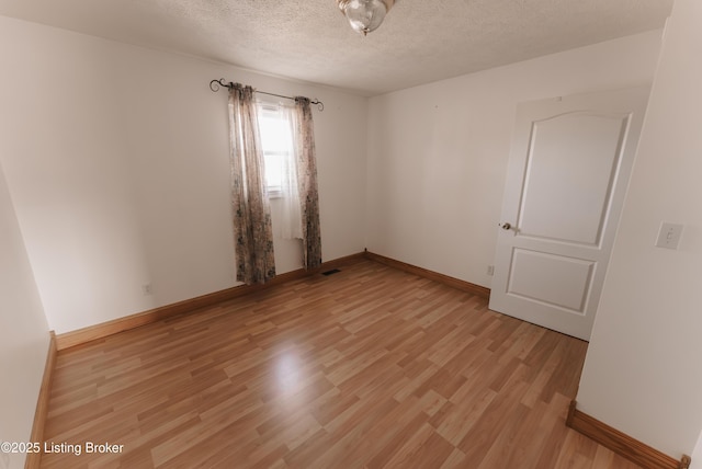 spare room with light hardwood / wood-style flooring and a textured ceiling