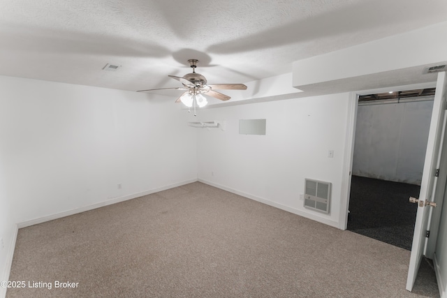 spare room with heating unit, ceiling fan, carpet, and a textured ceiling