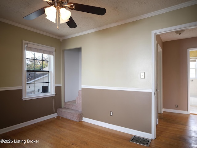 empty room with hardwood / wood-style floors, a textured ceiling, ceiling fan, and ornamental molding