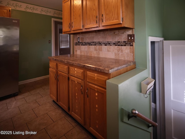 kitchen with backsplash, stainless steel refrigerator, and tile patterned floors