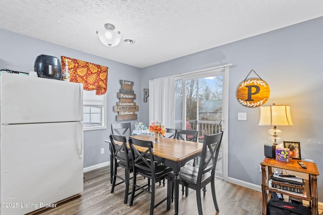 dining space featuring hardwood / wood-style floors, a textured ceiling, and a healthy amount of sunlight