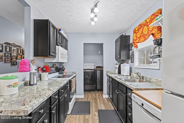 kitchen featuring a textured ceiling, white appliances, sink, washer and dryer, and light hardwood / wood-style flooring