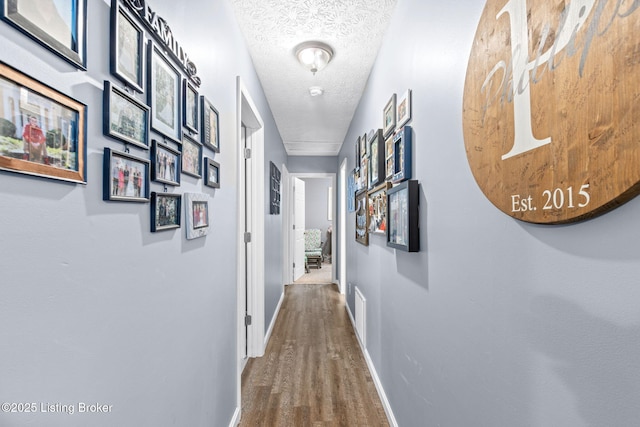 hall with wood-type flooring and a textured ceiling