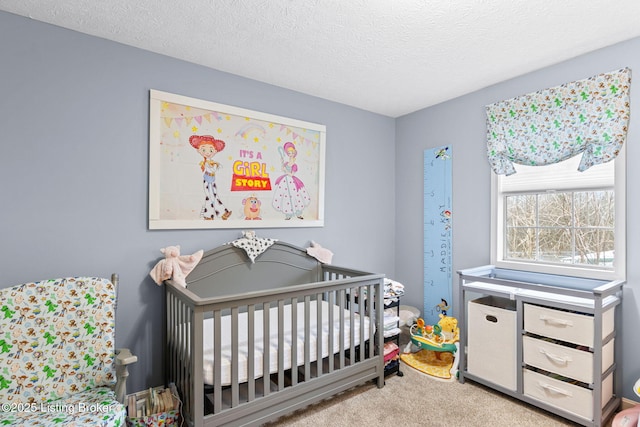 bedroom with light carpet, a nursery area, and a textured ceiling