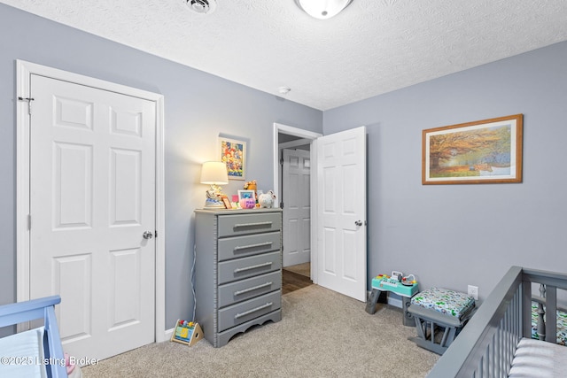 carpeted bedroom featuring a crib and a textured ceiling