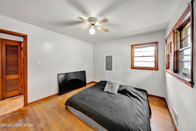 bedroom featuring electric panel, light hardwood / wood-style floors, and ceiling fan