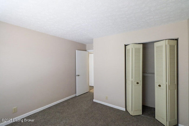 unfurnished bedroom featuring a closet, a textured ceiling, and dark colored carpet