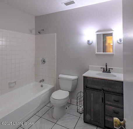 full bathroom featuring vanity, toilet, tiled shower / bath combo, and a textured ceiling