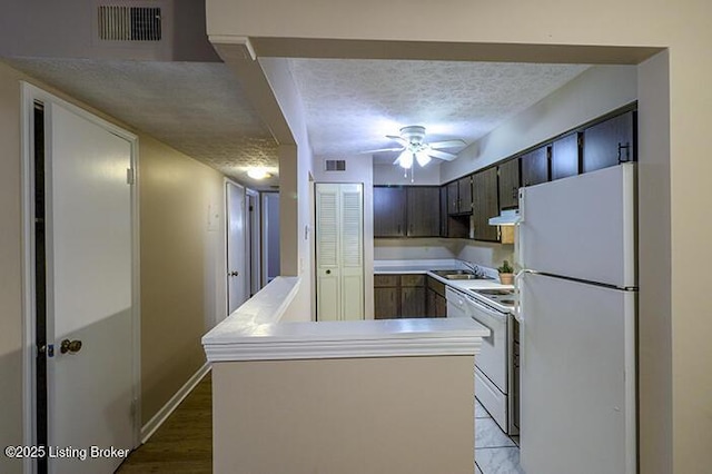 kitchen featuring dark brown cabinetry, sink, a textured ceiling, kitchen peninsula, and white appliances