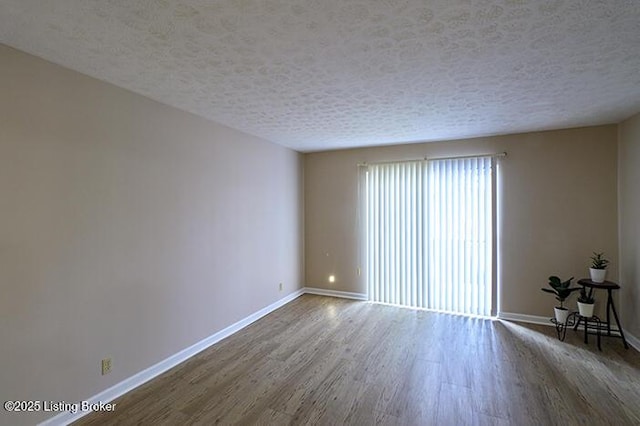 empty room with dark hardwood / wood-style floors and a textured ceiling