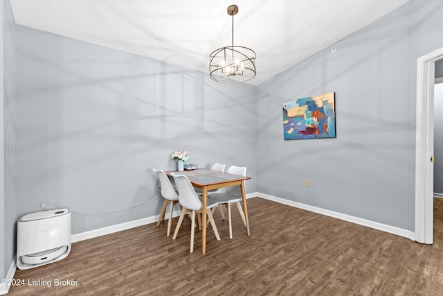 dining room with dark wood-type flooring and an inviting chandelier