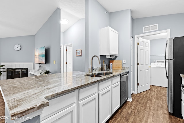 kitchen featuring lofted ceiling, sink, light stone counters, white cabinetry, and stainless steel appliances