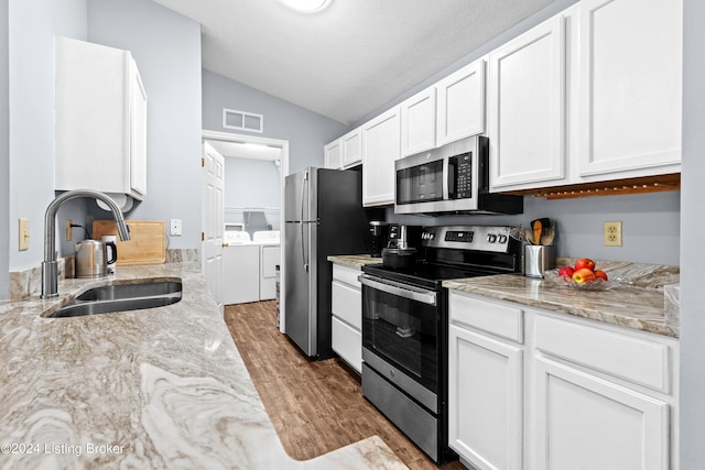 kitchen featuring white cabinets, washing machine and dryer, stainless steel appliances, and sink