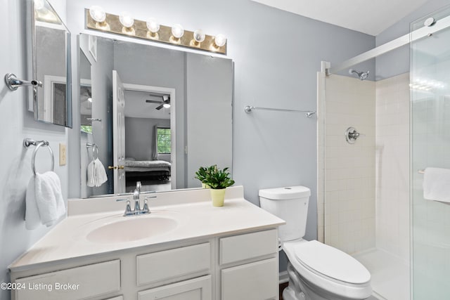 bathroom with ceiling fan, a shower with door, vanity, and toilet