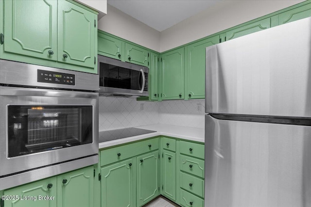 kitchen featuring backsplash, green cabinets, and stainless steel appliances