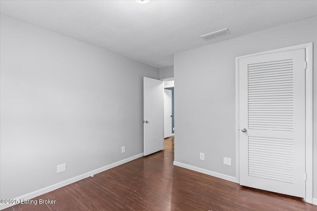 unfurnished bedroom featuring a closet, dark hardwood / wood-style flooring, and a textured ceiling