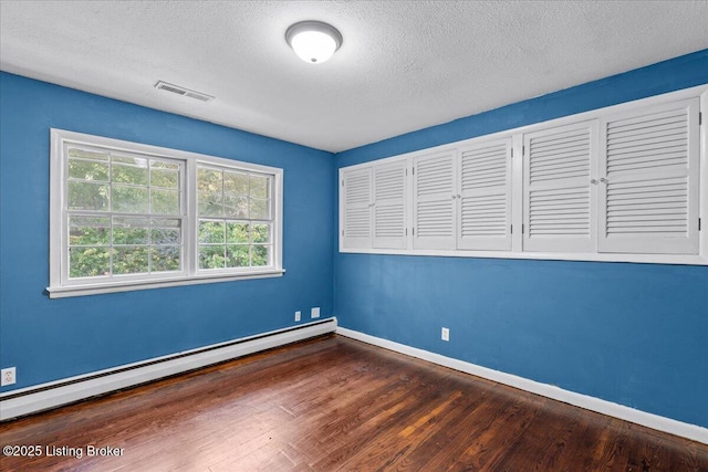 spare room with dark hardwood / wood-style flooring, a baseboard radiator, and a textured ceiling