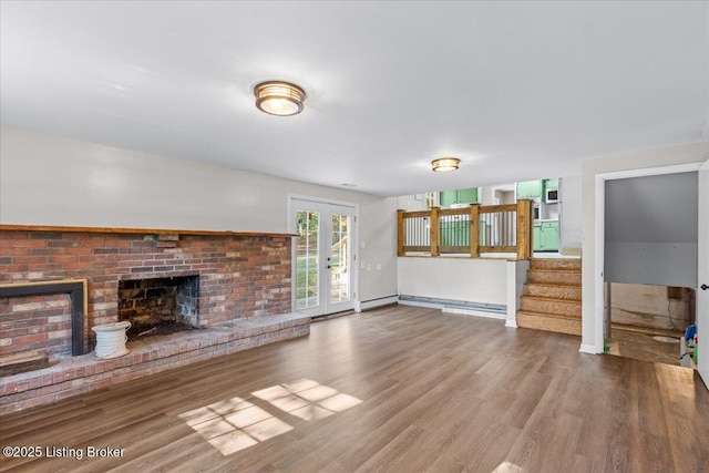 unfurnished living room with hardwood / wood-style floors, french doors, and a brick fireplace