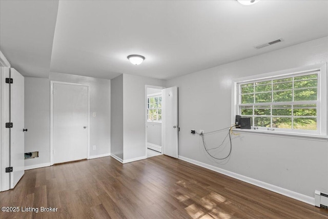 unfurnished room featuring dark hardwood / wood-style floors, a healthy amount of sunlight, and baseboard heating