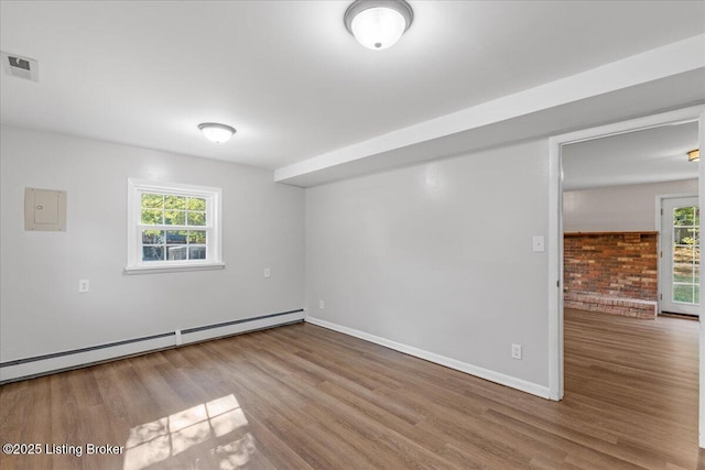 unfurnished room with light wood-type flooring and a baseboard heating unit