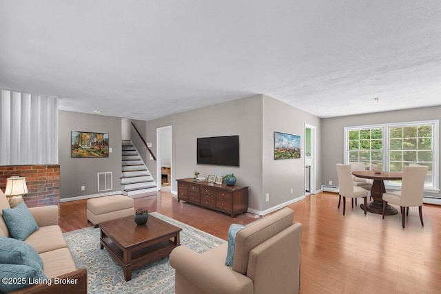 living room featuring light wood-type flooring and a baseboard heating unit