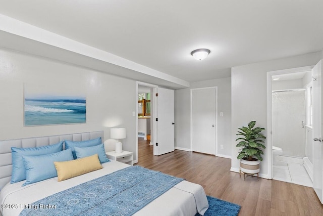 bedroom with ensuite bathroom and dark wood-type flooring