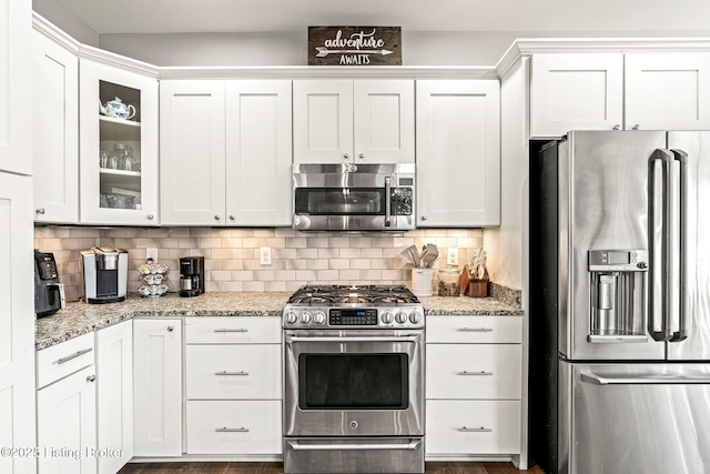 kitchen featuring white cabinets, light stone counters, stainless steel appliances, and tasteful backsplash