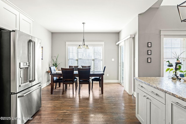 dining area featuring a healthy amount of sunlight, dark wood-type flooring, and a chandelier