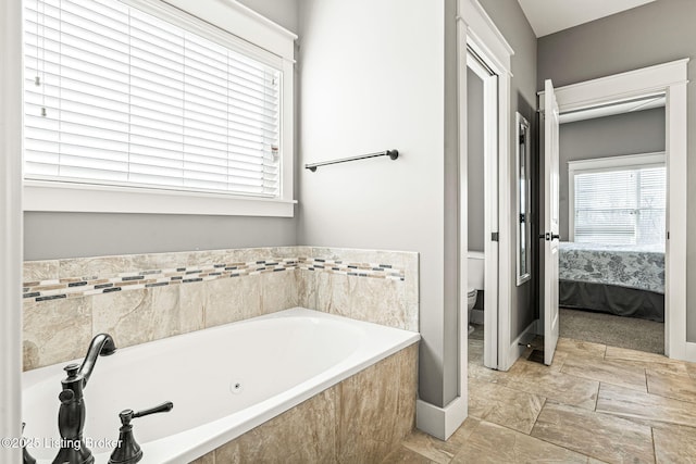 bathroom featuring toilet and tiled bath